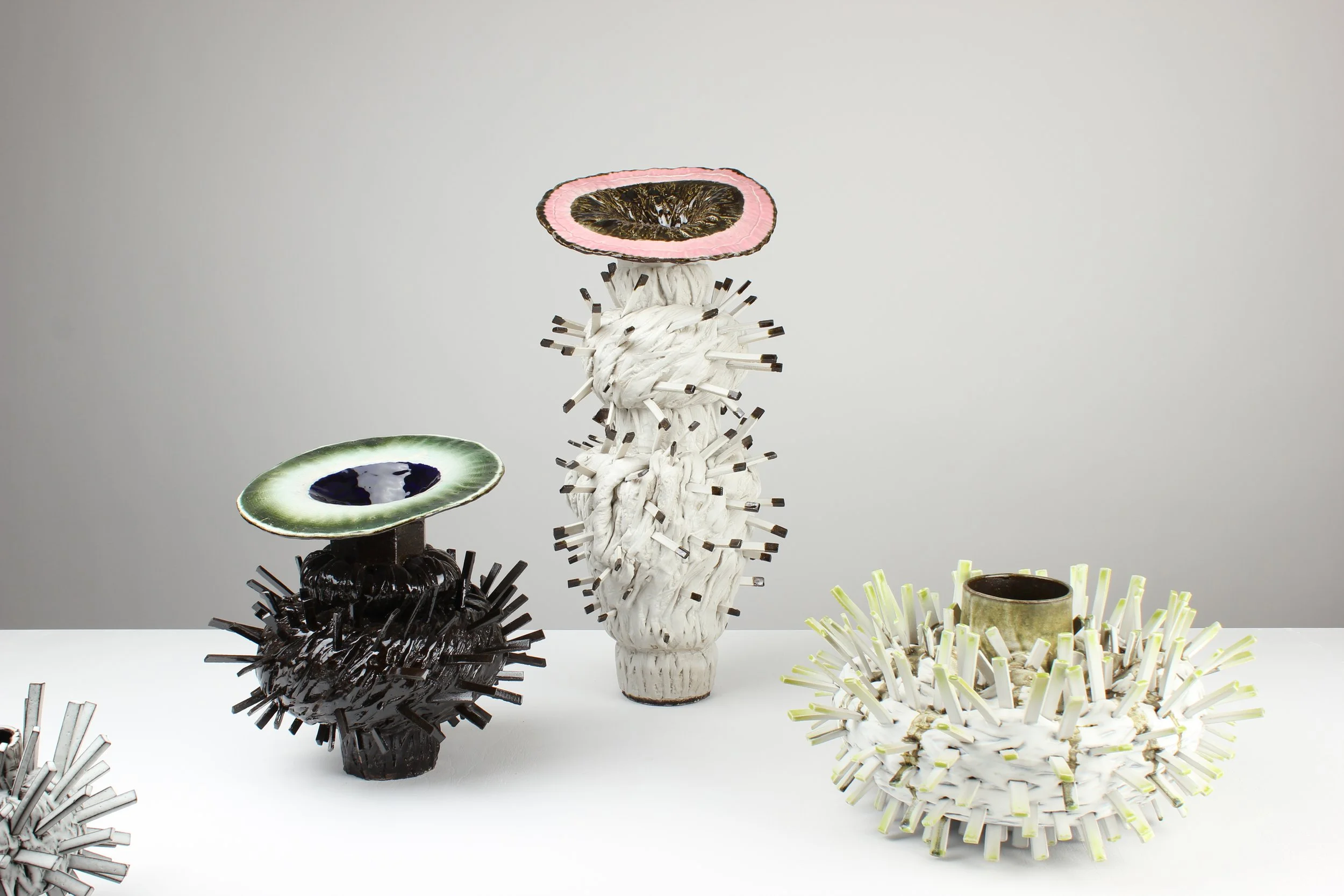 Kunstwerke aus recyceltem Material, die wie Tiere und Pflanzen aussehen, auf weißem Hintergrund.