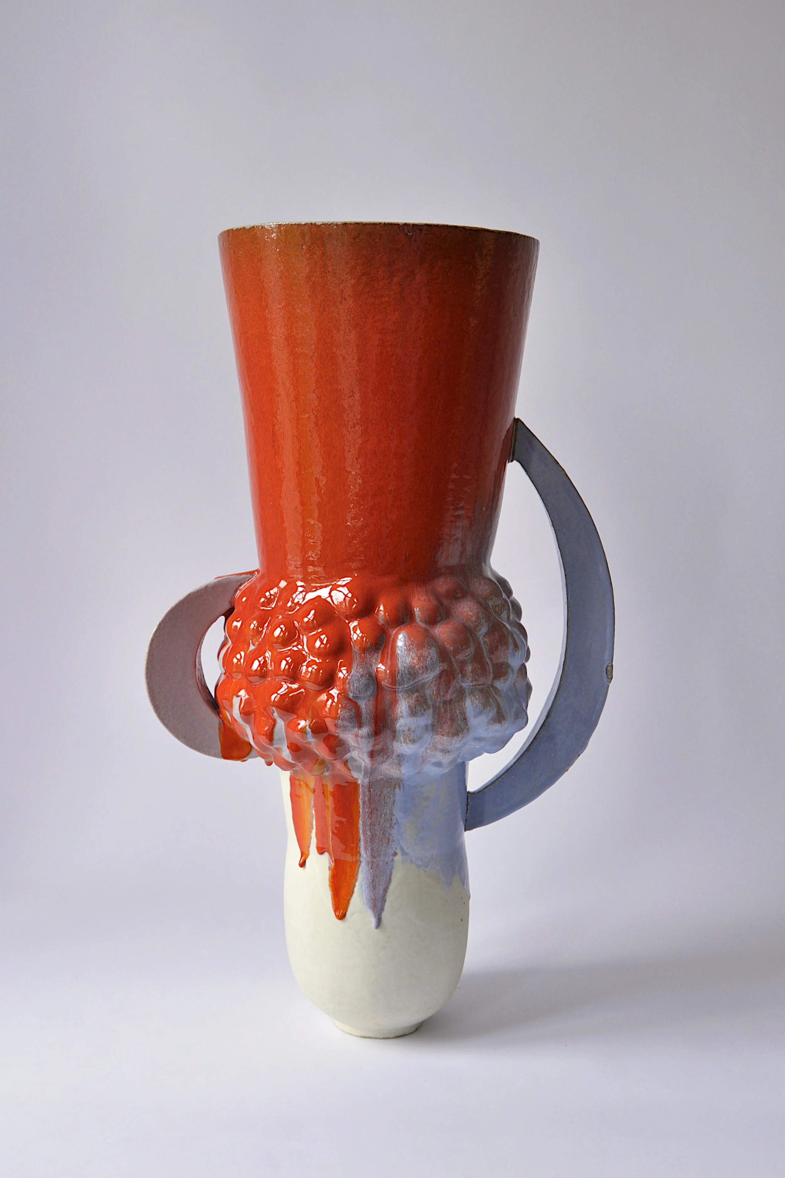 Ein Keramiktasse mit einem flüssigen, orangefarbenen Inhalt, der über den Rand läuft, auf einer weißen Basis. Der Hintergrund ist hellgrau.