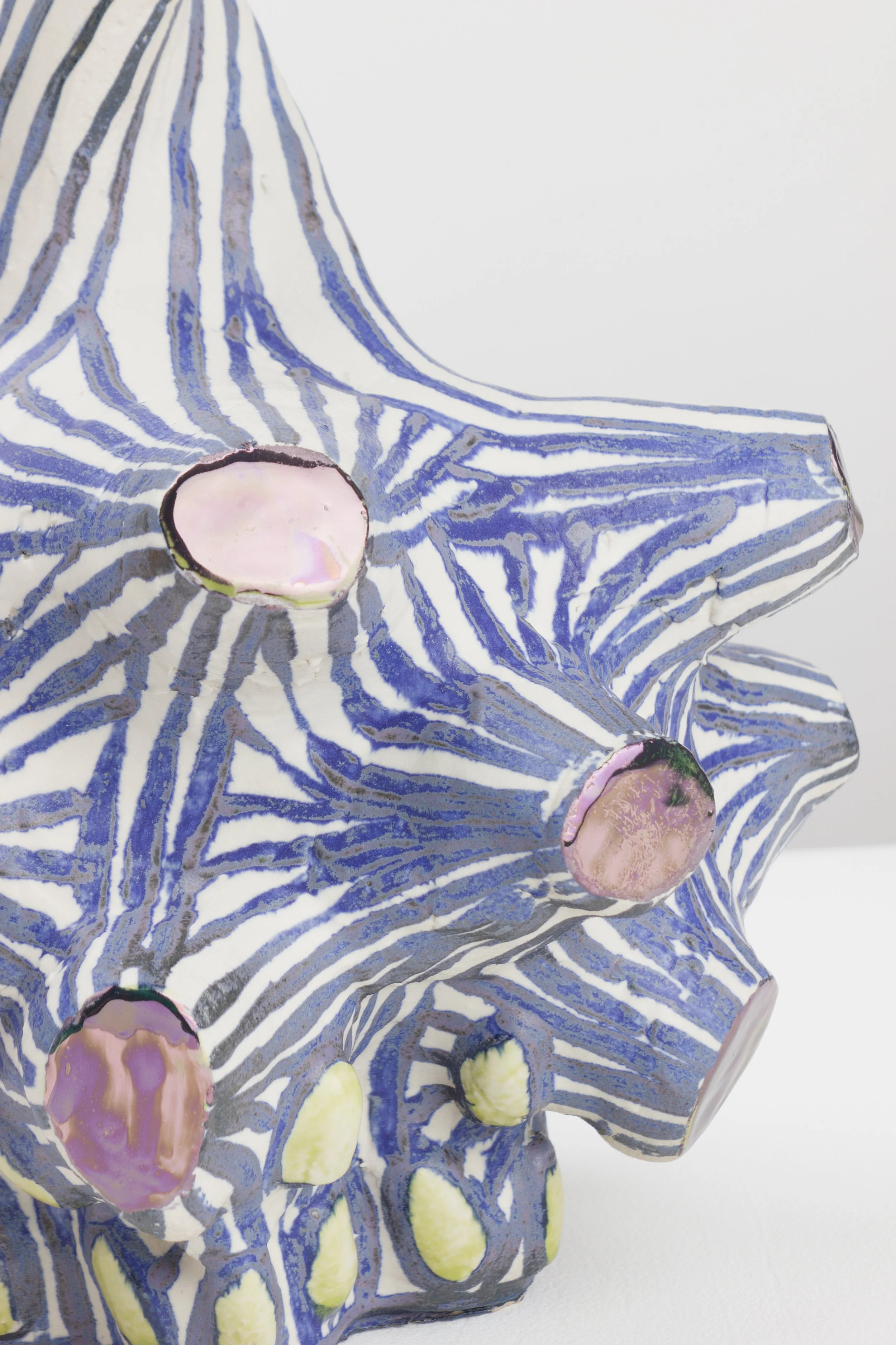 Kunstwerk aus Keramik mit blauen und weißen Streifen und eingefügten ovalen und kugeligen Elementen in Pastellfarben.