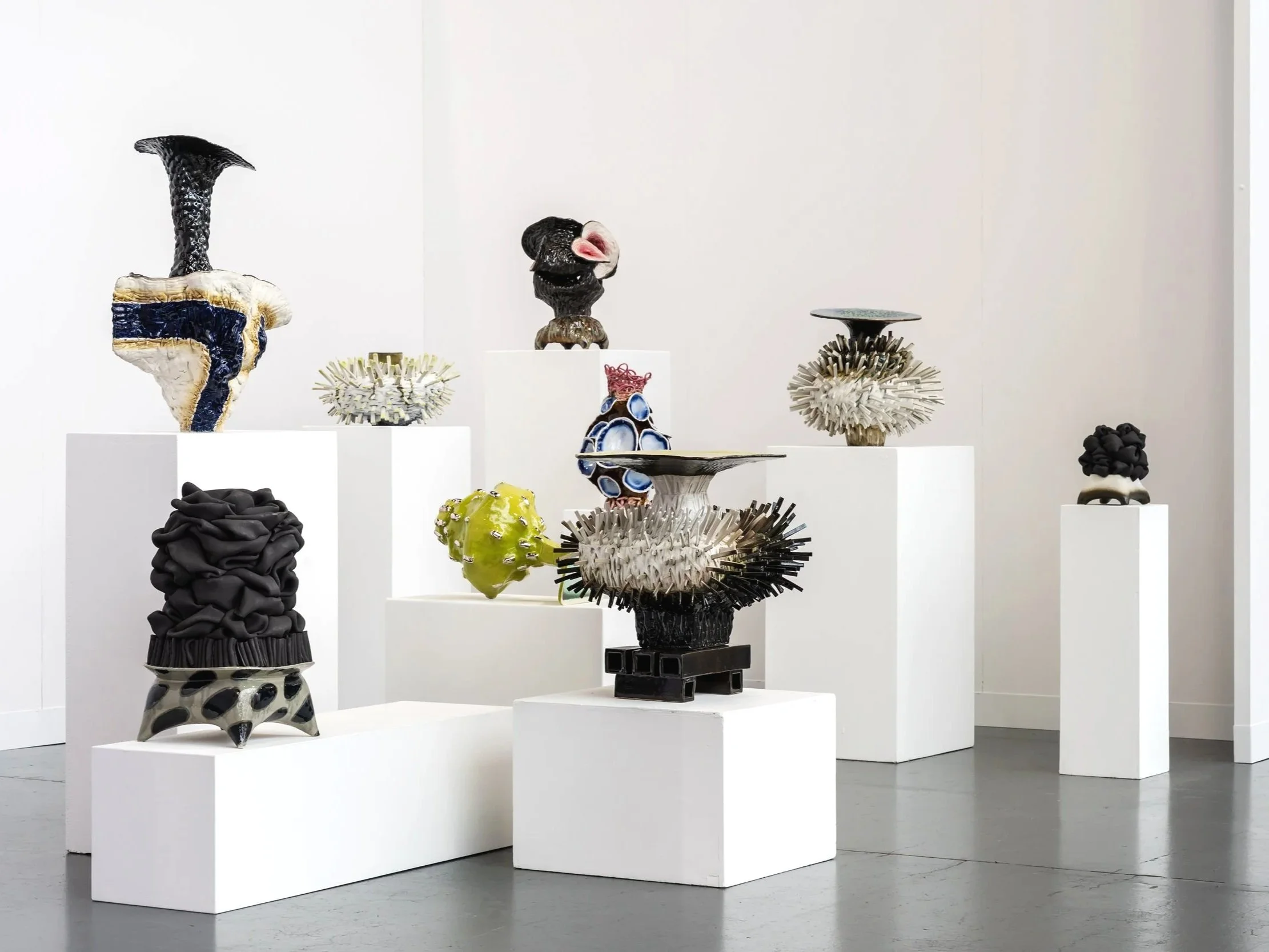 Kunstwerke auf weißen Podesten in einer Galerie