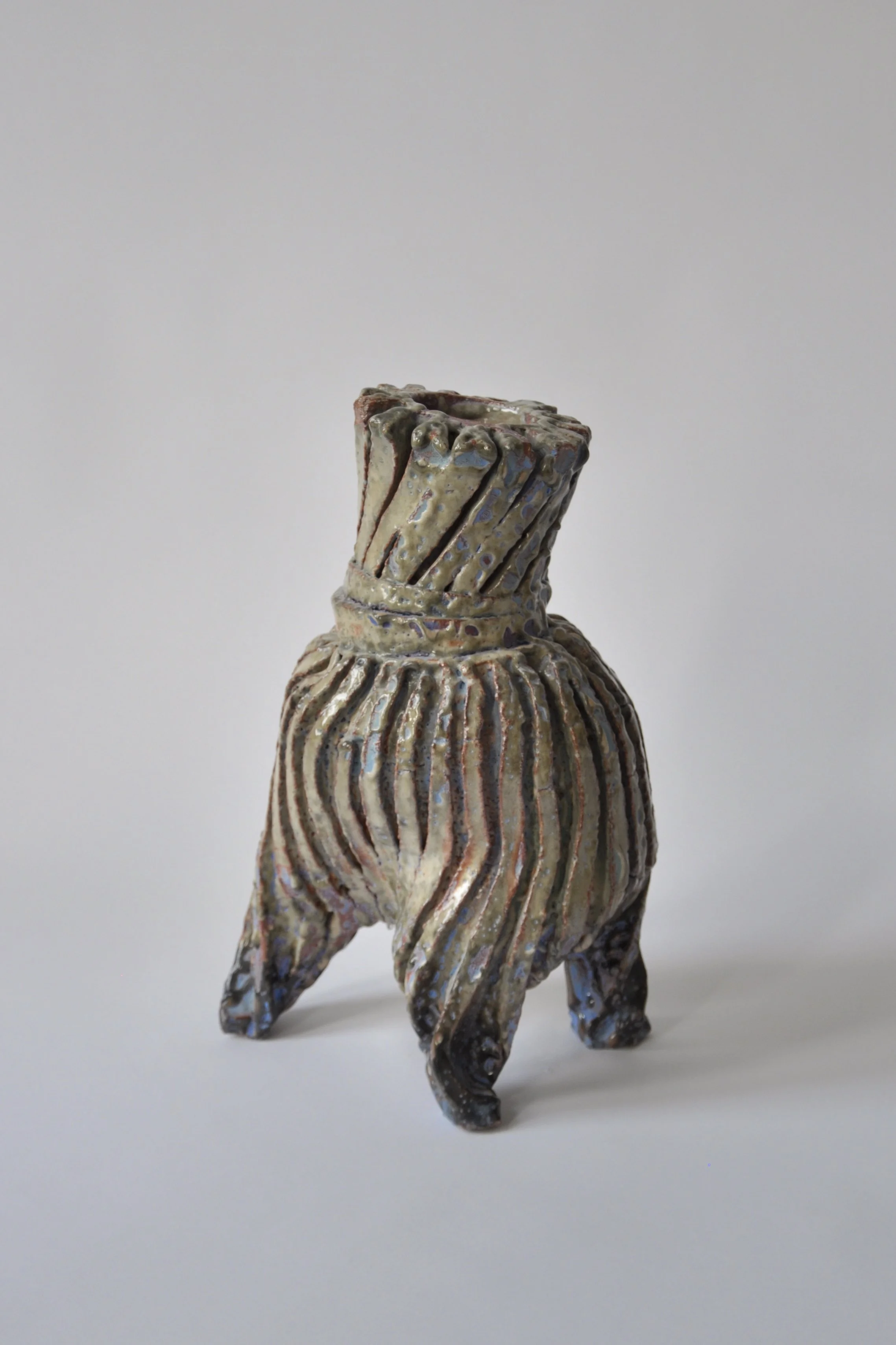 Keramikfigur eines Tieres, das wie ein Elefant aussieht, mit einem gewölbten Rücken und kurzen Beinen, auf einem weißen Hintergrund.