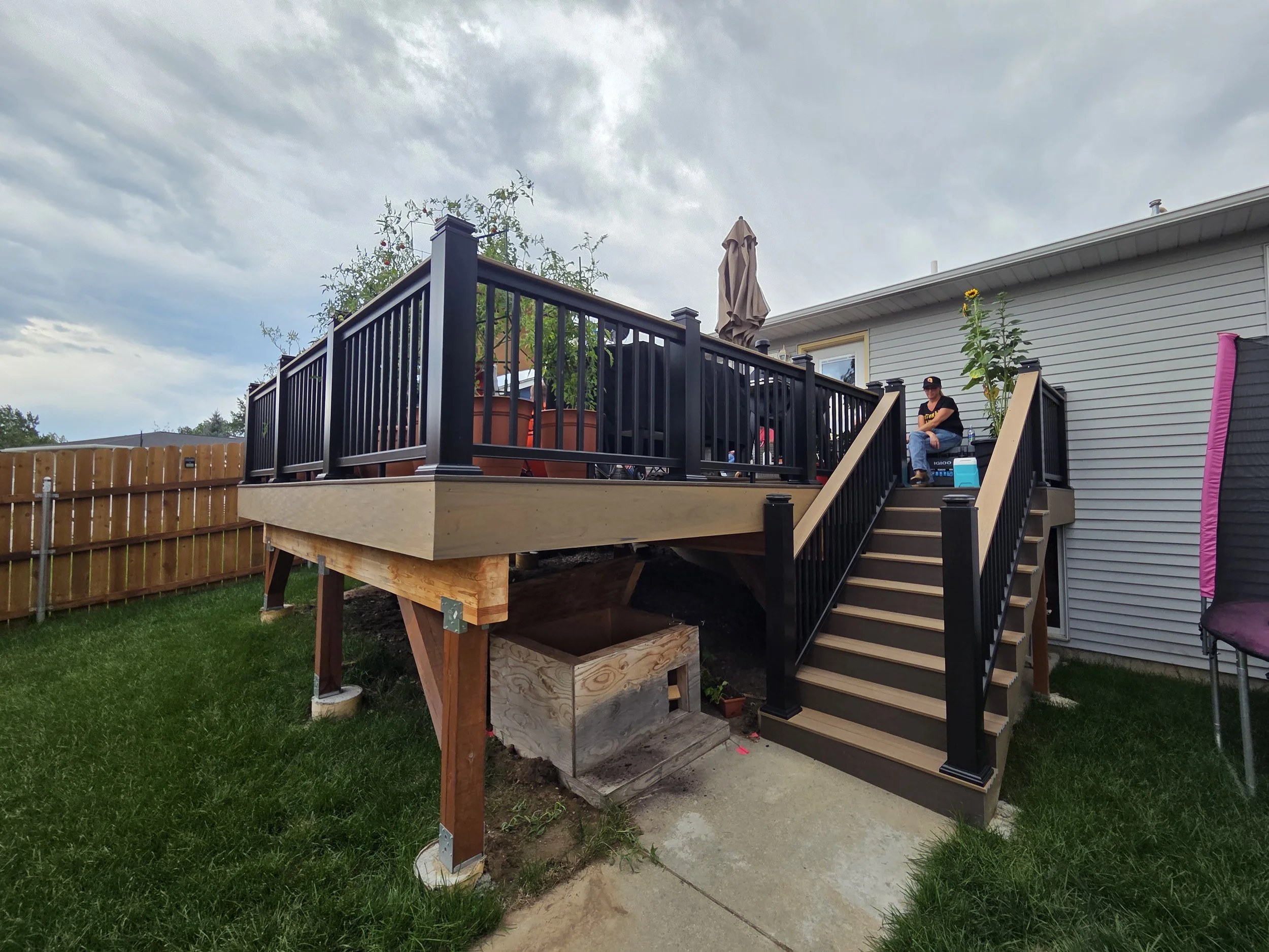 Custom backyard deck with black railings and wooden stairs in Logan, Utah