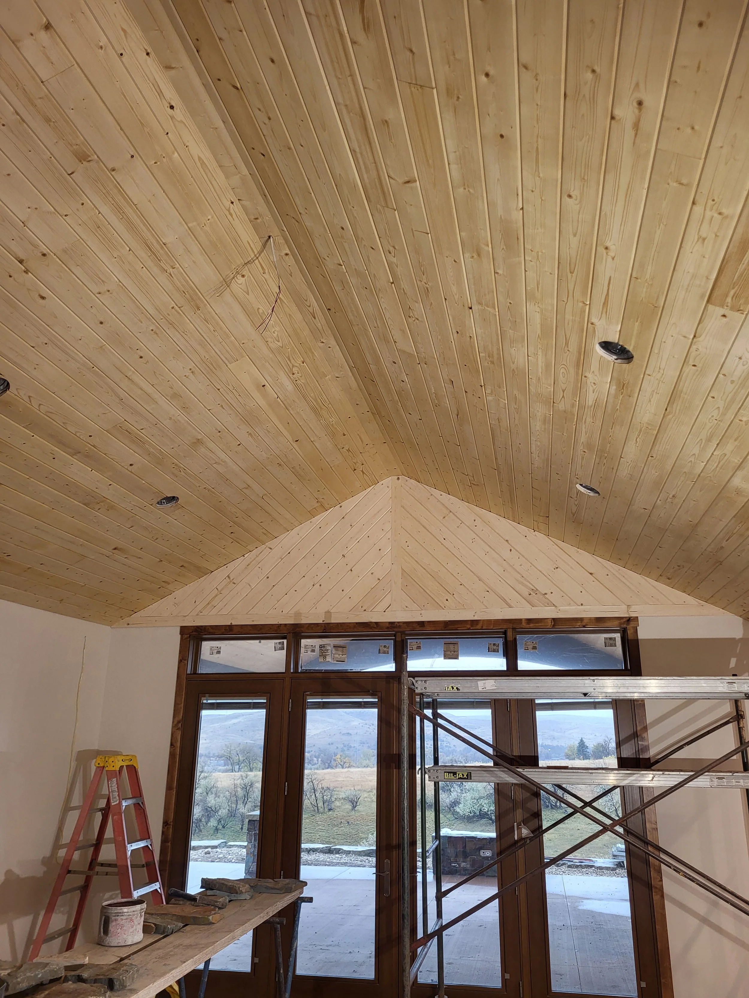 Completed room renovation with custom wood ceiling and large windows in Logan, Utah