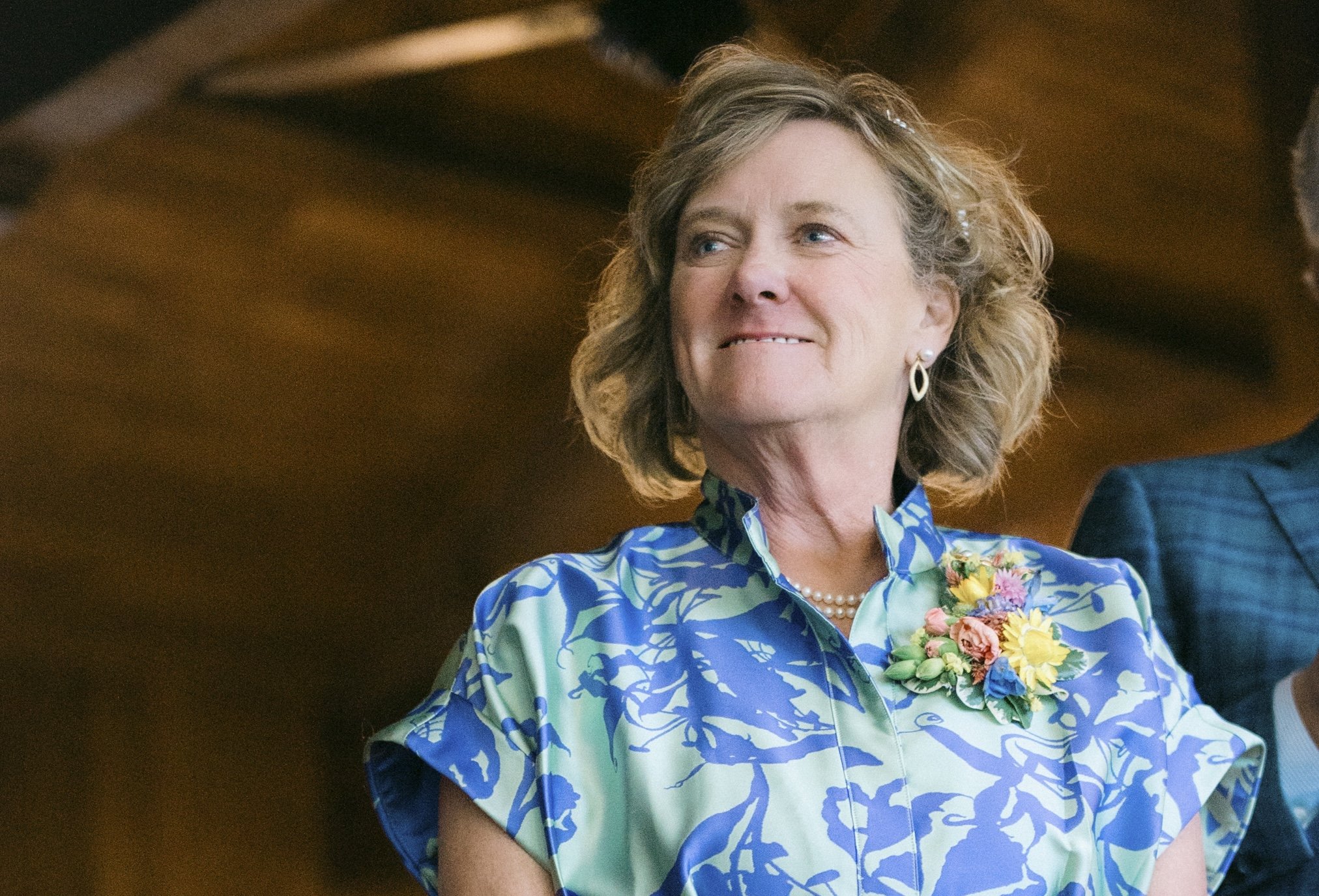 Kathy Tanner, Mayoral Candidate for Lake Lure North Carolina, stands wearing a green and blue dress, smiling over her right shoulder
