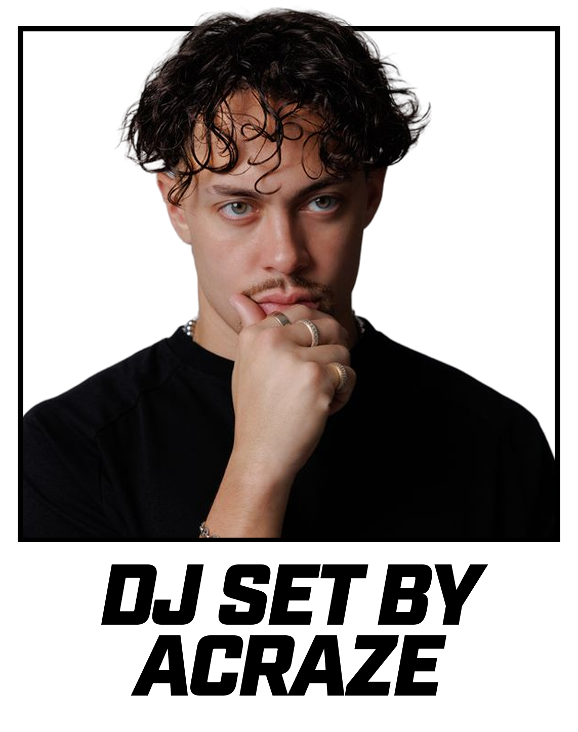 Young man with curly dark hair, blue eyes, wearing rings and a black shirt, touching his lips with his hand, against a plain black background.