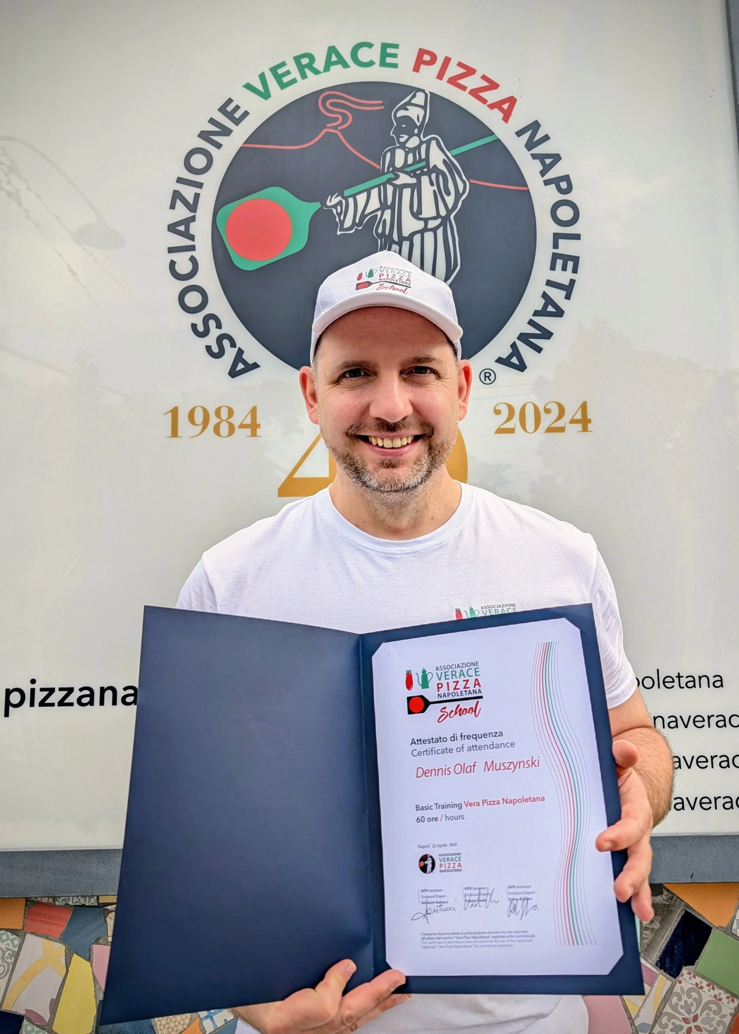 Der MEZZA Gründer und Inhaber hält ein Zertifikat der AVPN. Er trägt ein weißes Cap und ein weißes T-Shirt.