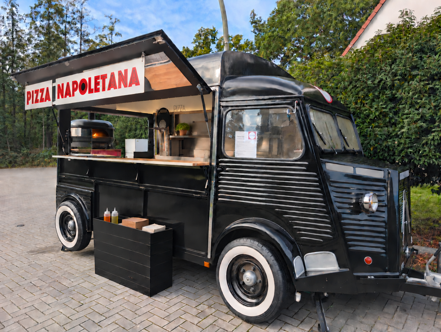 Ein schwarzer Food-Truck, der Pizza verkauft, mit einem Schild 'Pizza Napoletana'.