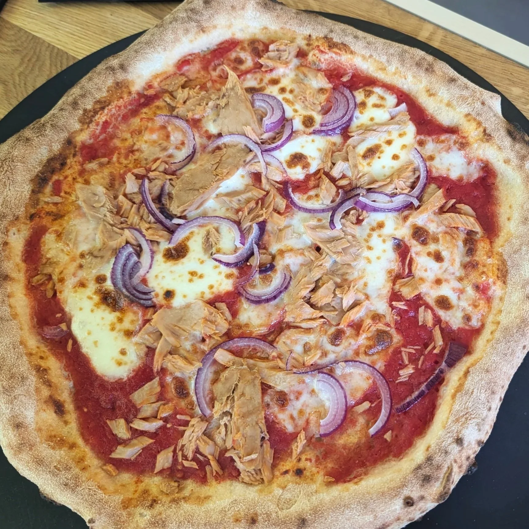 Pizza mit Tomatensauce, Mozzarella, rote Zwiebeln und Thunfisch
