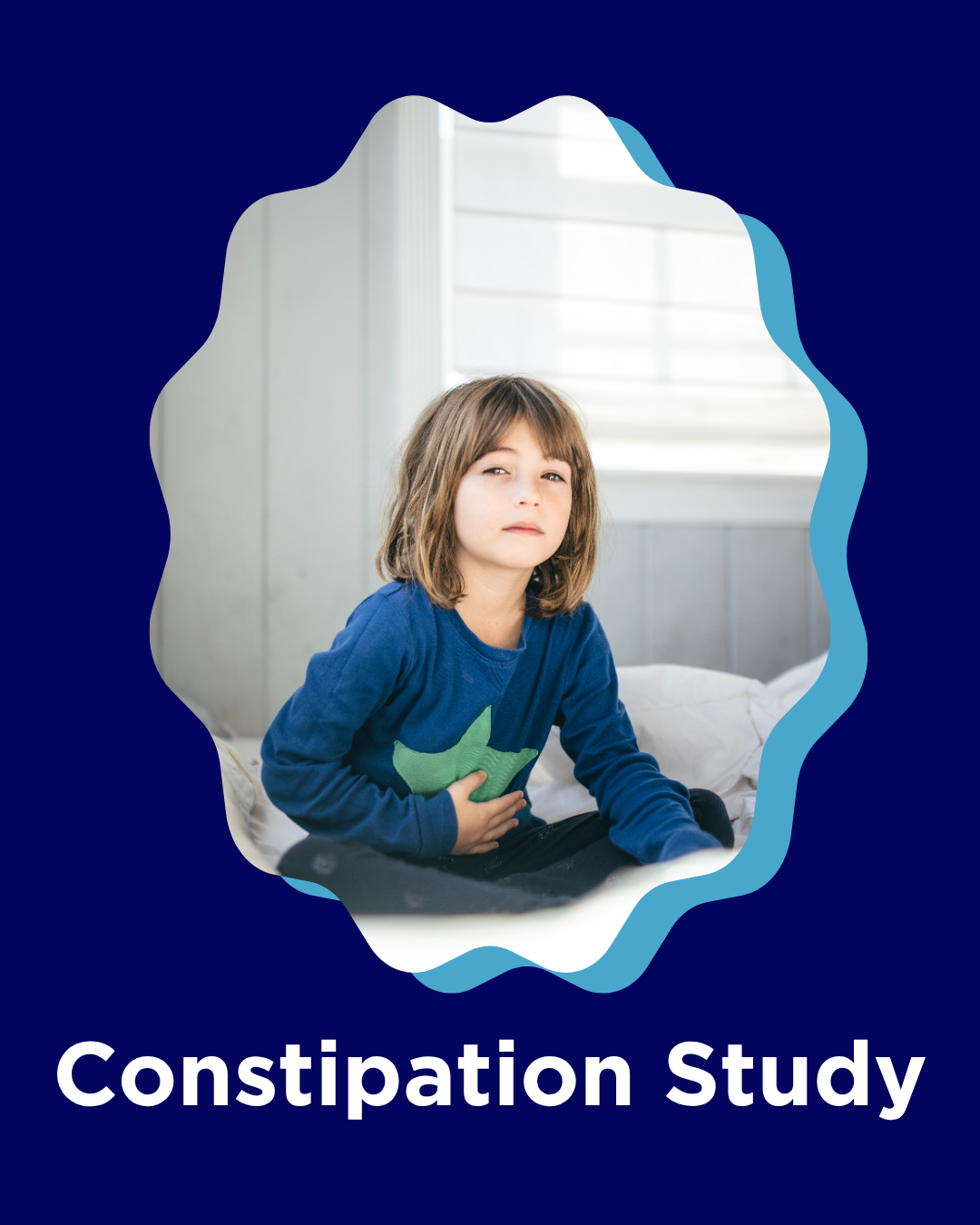 A young girl sitting on a bed with her hand on her stomach, looking uncomfortable, with a window in the background, indicating a constipation study.