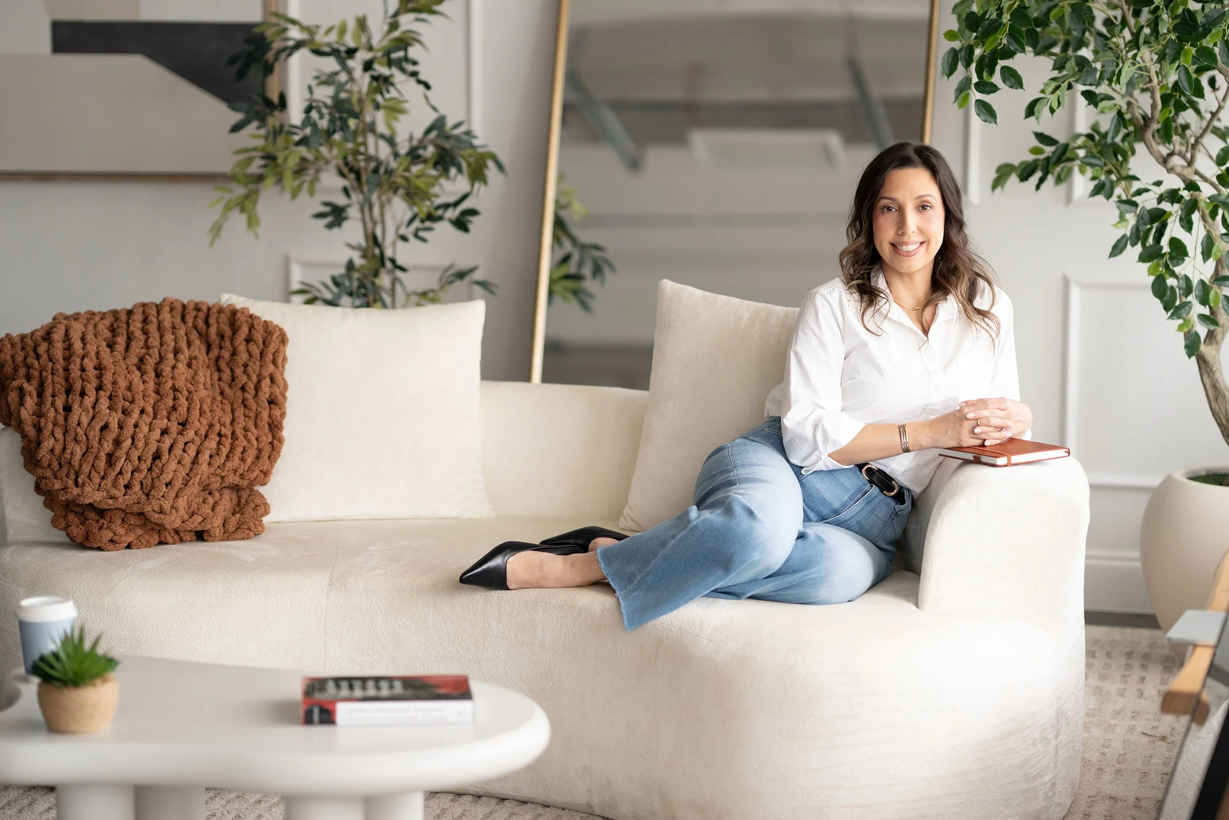 Leslie Gil seated on a white couch.