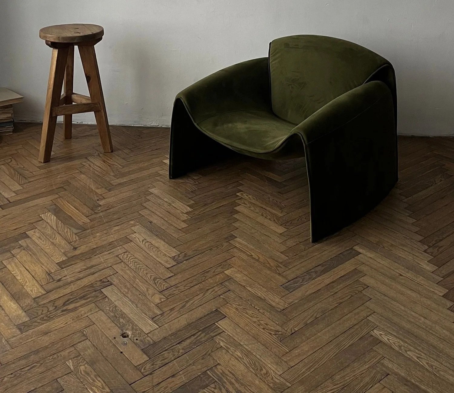Dark green upholstered chair and wooden stool in a welcoming interior.