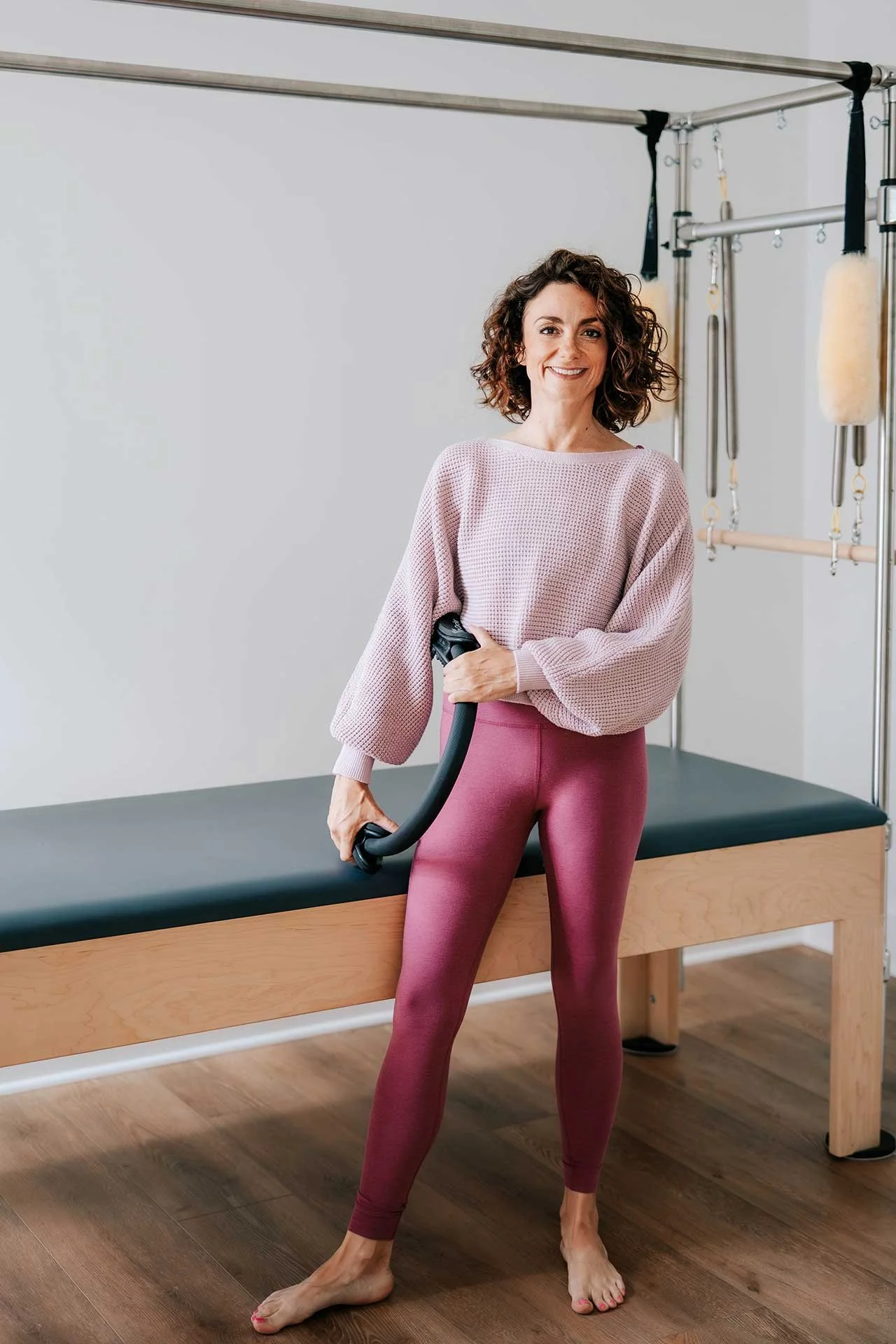 Pilates instructor Kim Russell standing next to a reformer