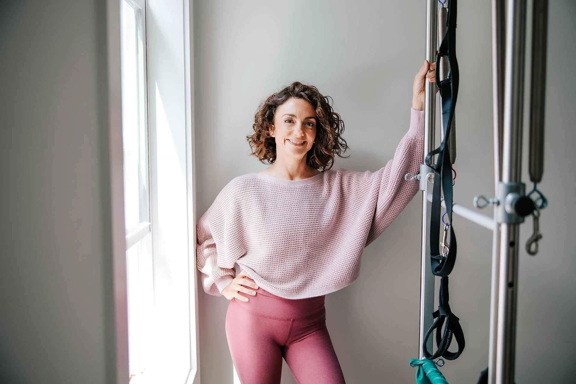 Pilates instructor Kim Russell wearing a pink outfit and smiling at the camera