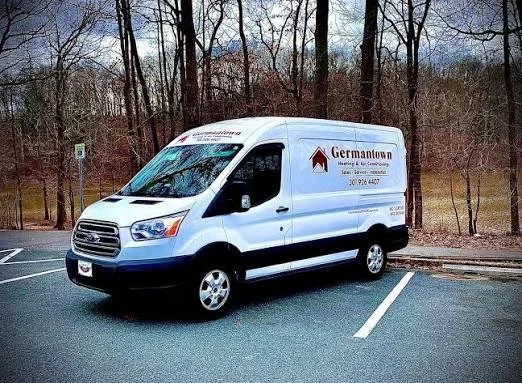 A white commercial van parked in a parking lot with trees in the background. The van has the logo and name "Germantown" on its side, along with contact information.
