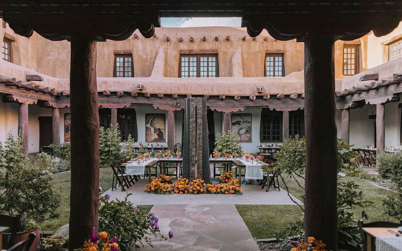 Traditional Tibetan courtyard restaurant with colorful flowers, outdoor dining tables, wooden columns, and painted wall murals