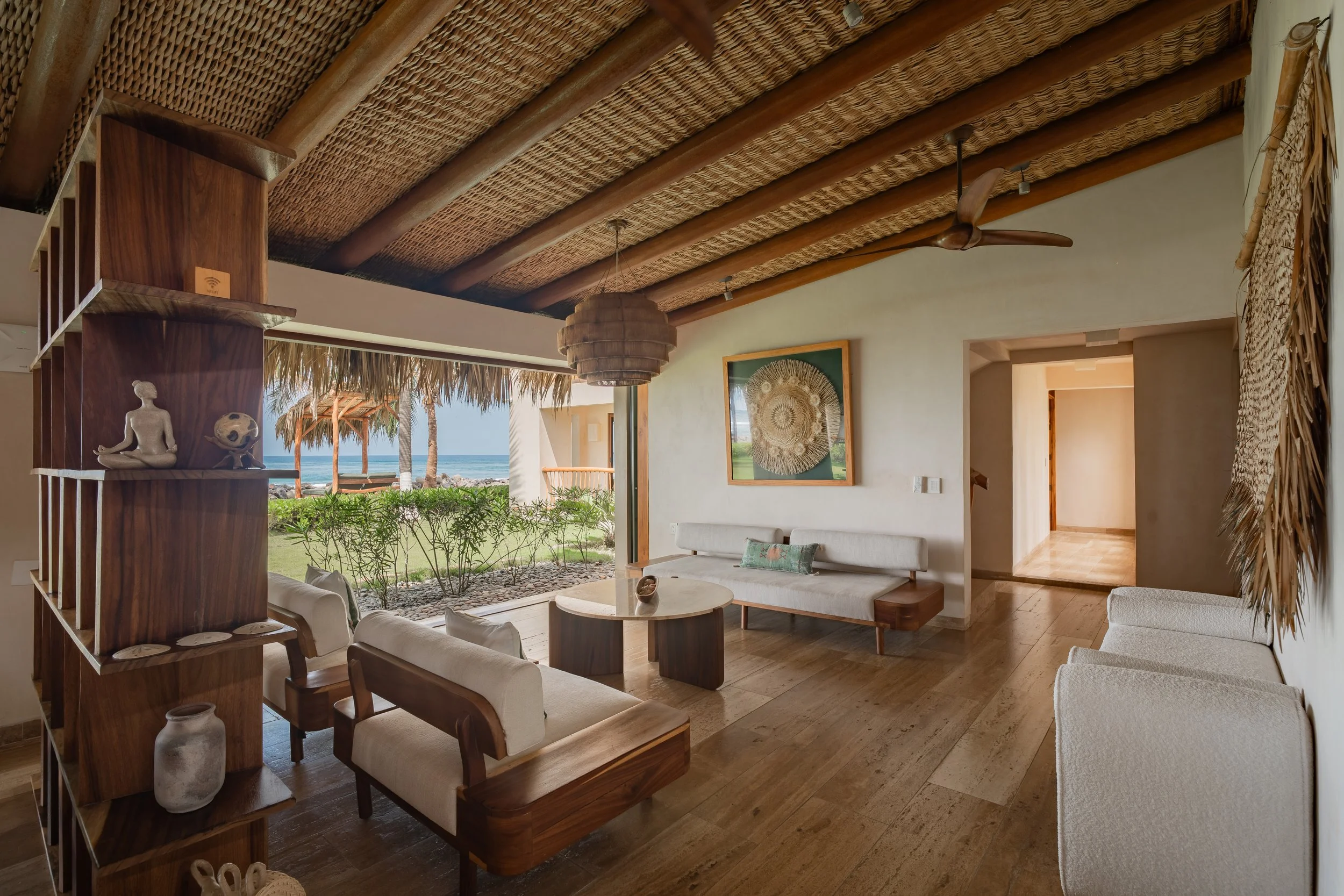 Beach house living room with ocean view, featuring a woven ceiling, ceiling fan, and tropical decor.