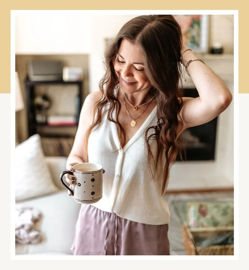 Emm at home holding a coffee in a bright, cozy living space.