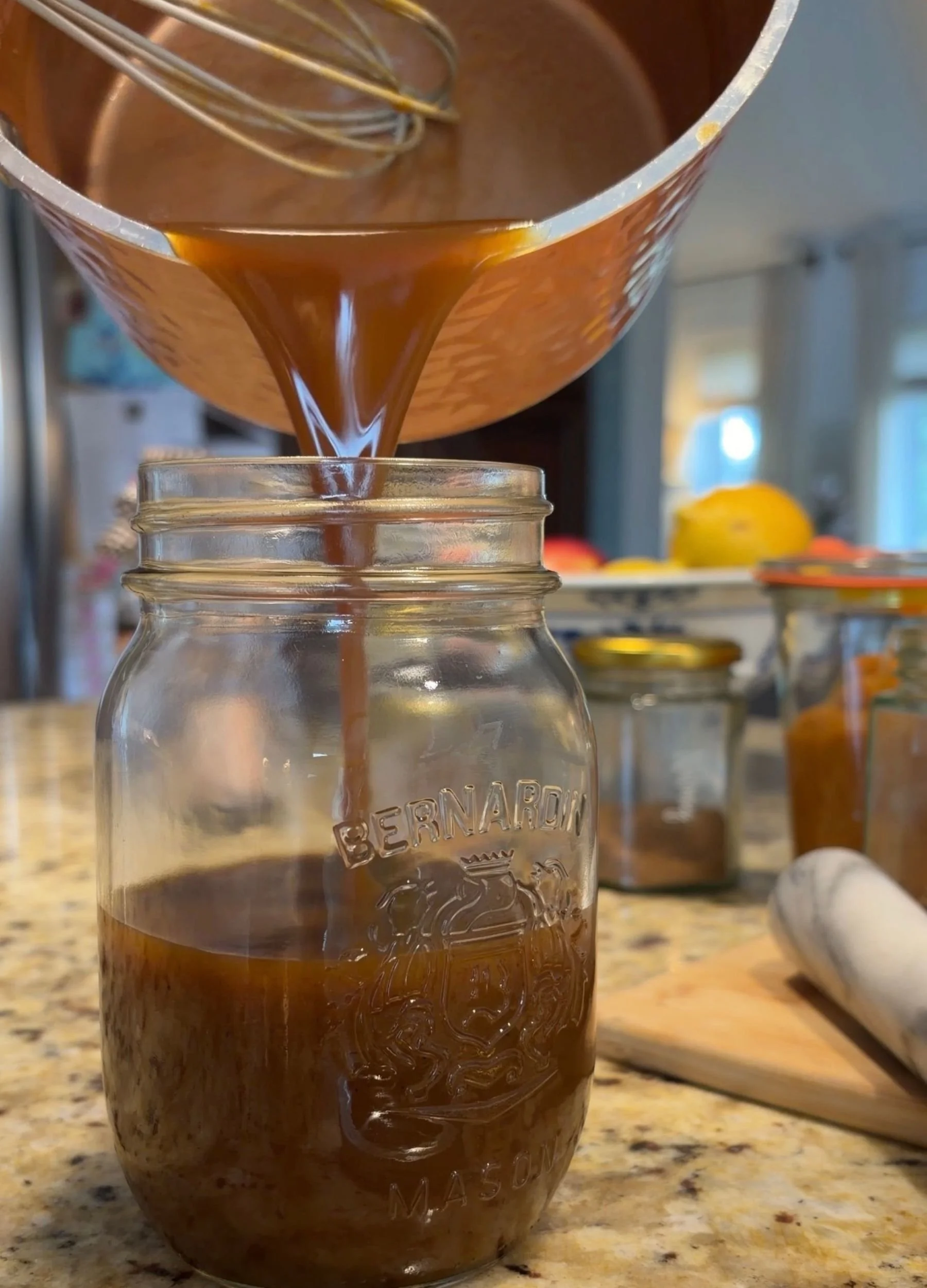 Homemade pumpkin spice syrup being poured into a glass mason jar