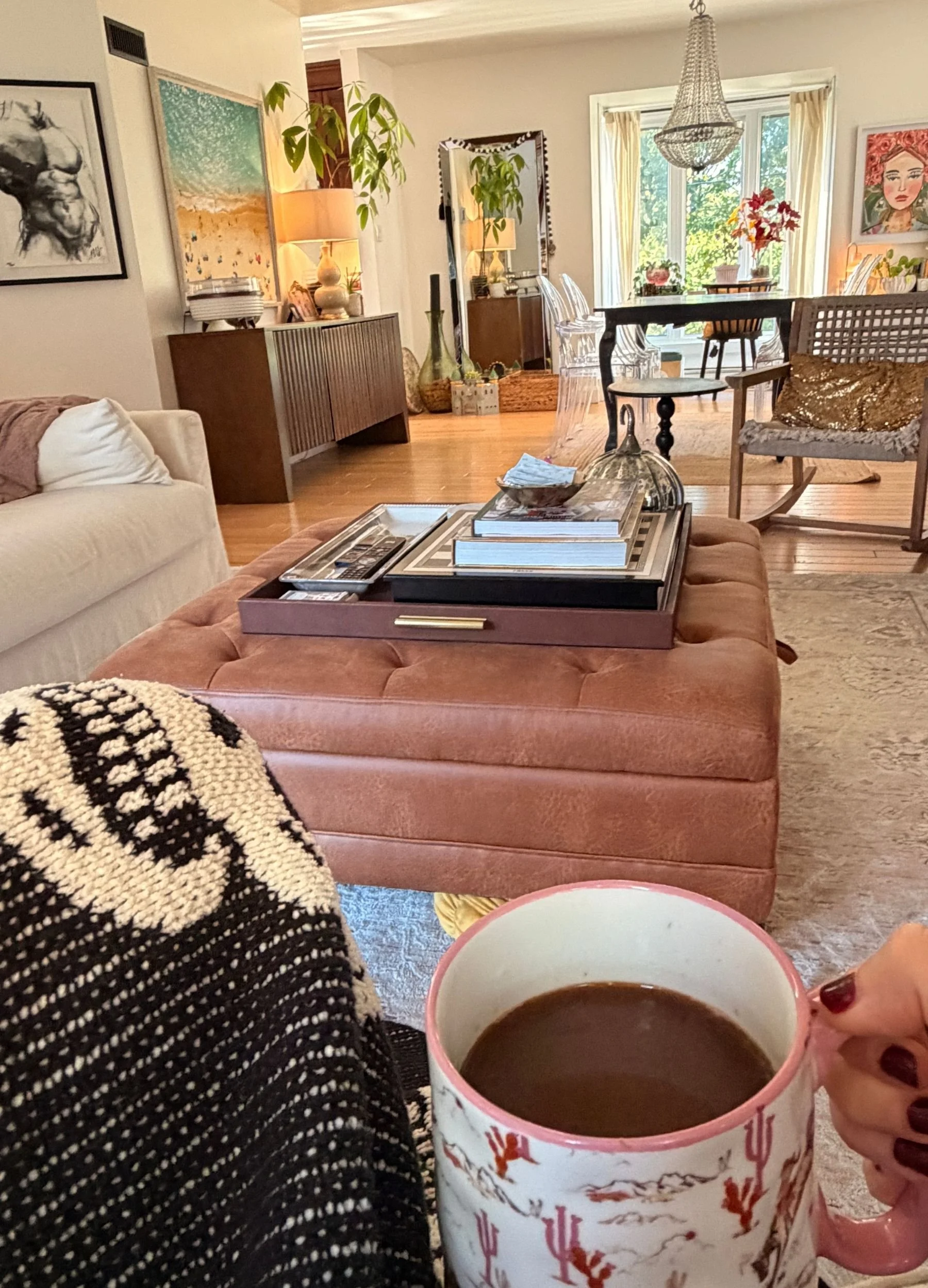 A cozy October morning at home with a cup of coffee, a patterned blanket, warm autumn decor and a sunlit living room.
