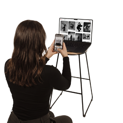 Woman taking a photo of a laptop screen displaying black and white images of yoga poses with her smartphone.