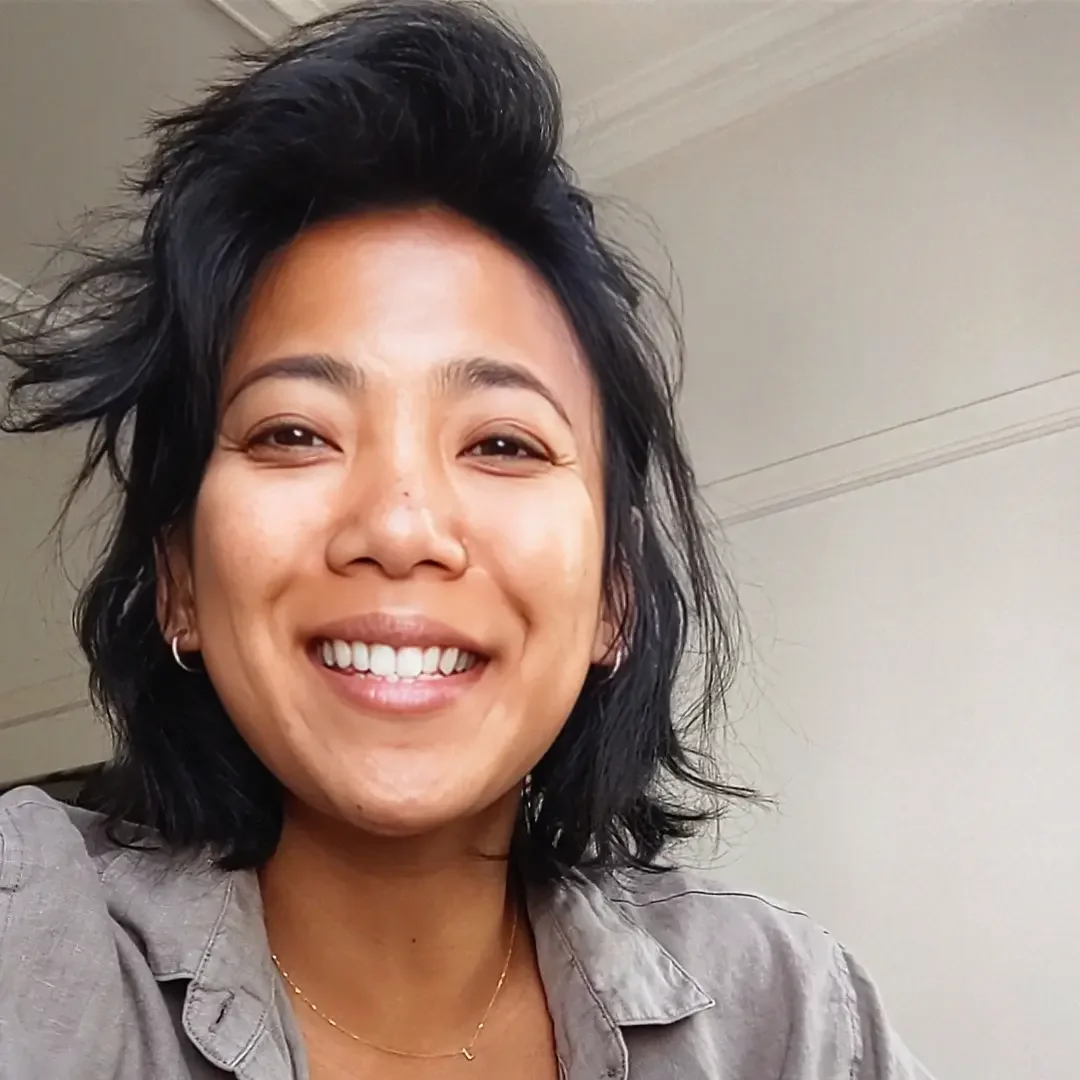 A woman with black, wavy hair smiling at the camera.