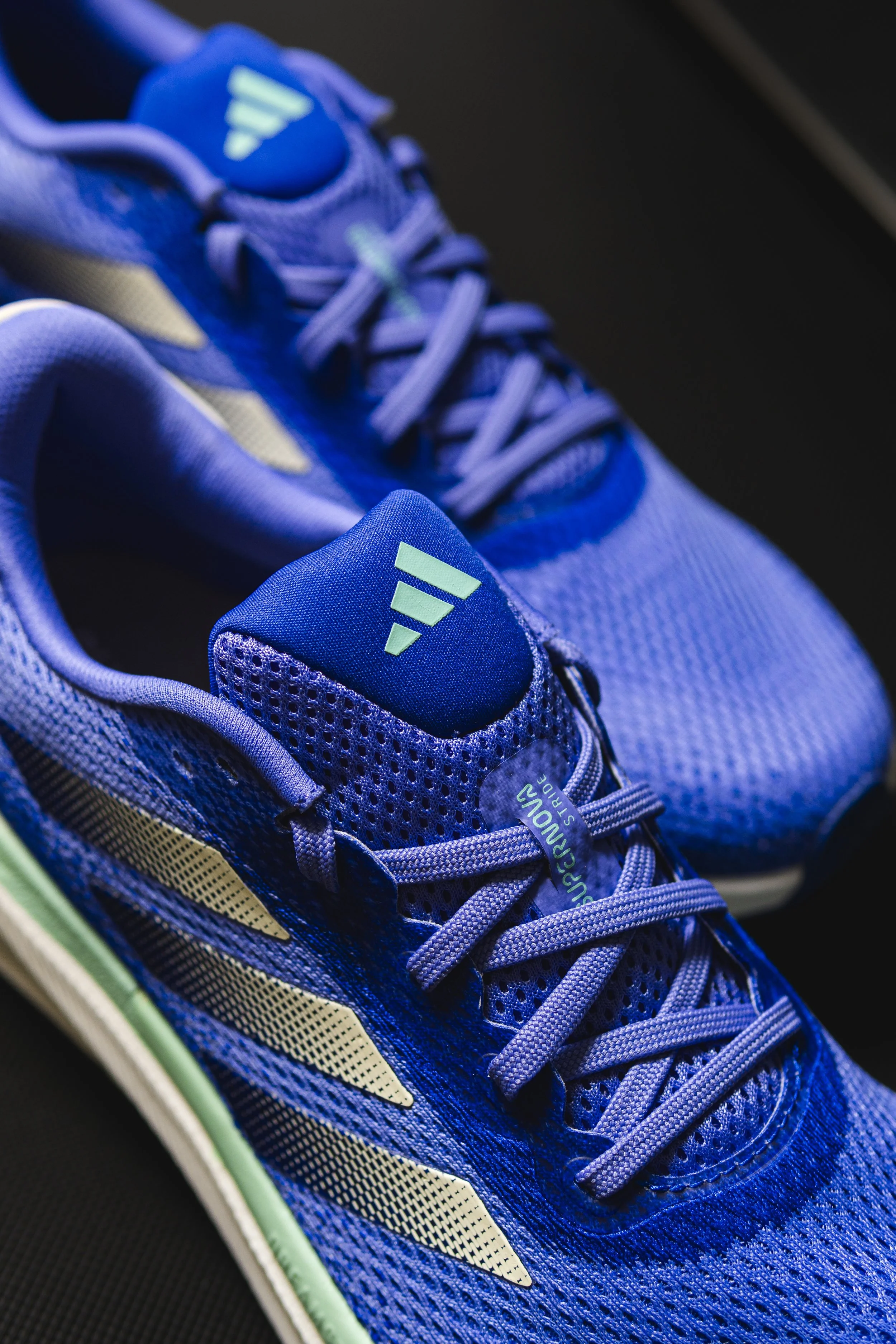Close-up of a blue athletic running shoe with light green accents and mesh details.