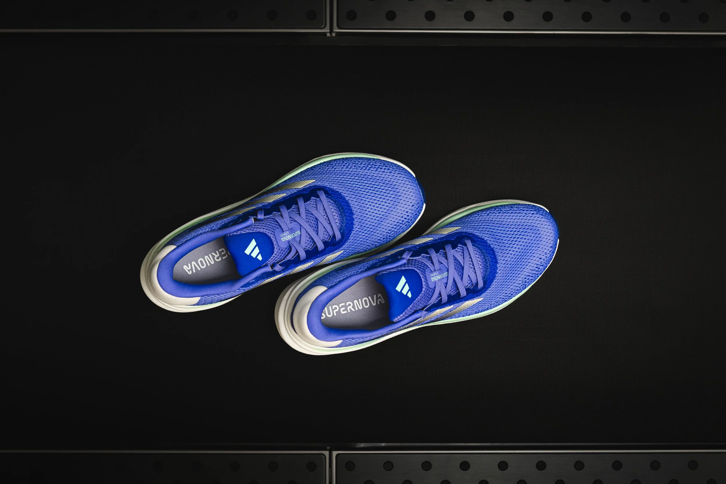 Pair of blue athletic shoes with gray and white accents on a black surface.