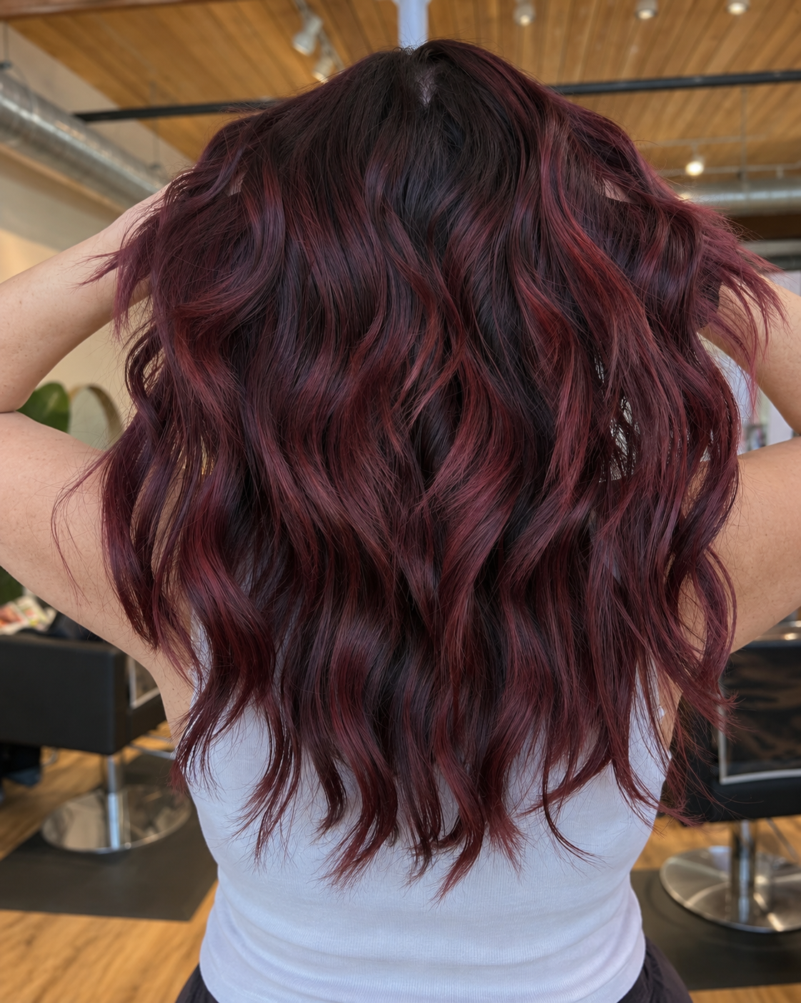 Dimensional burgundy red hair color on long waves at Raven Hair Studio in Palmer, AK