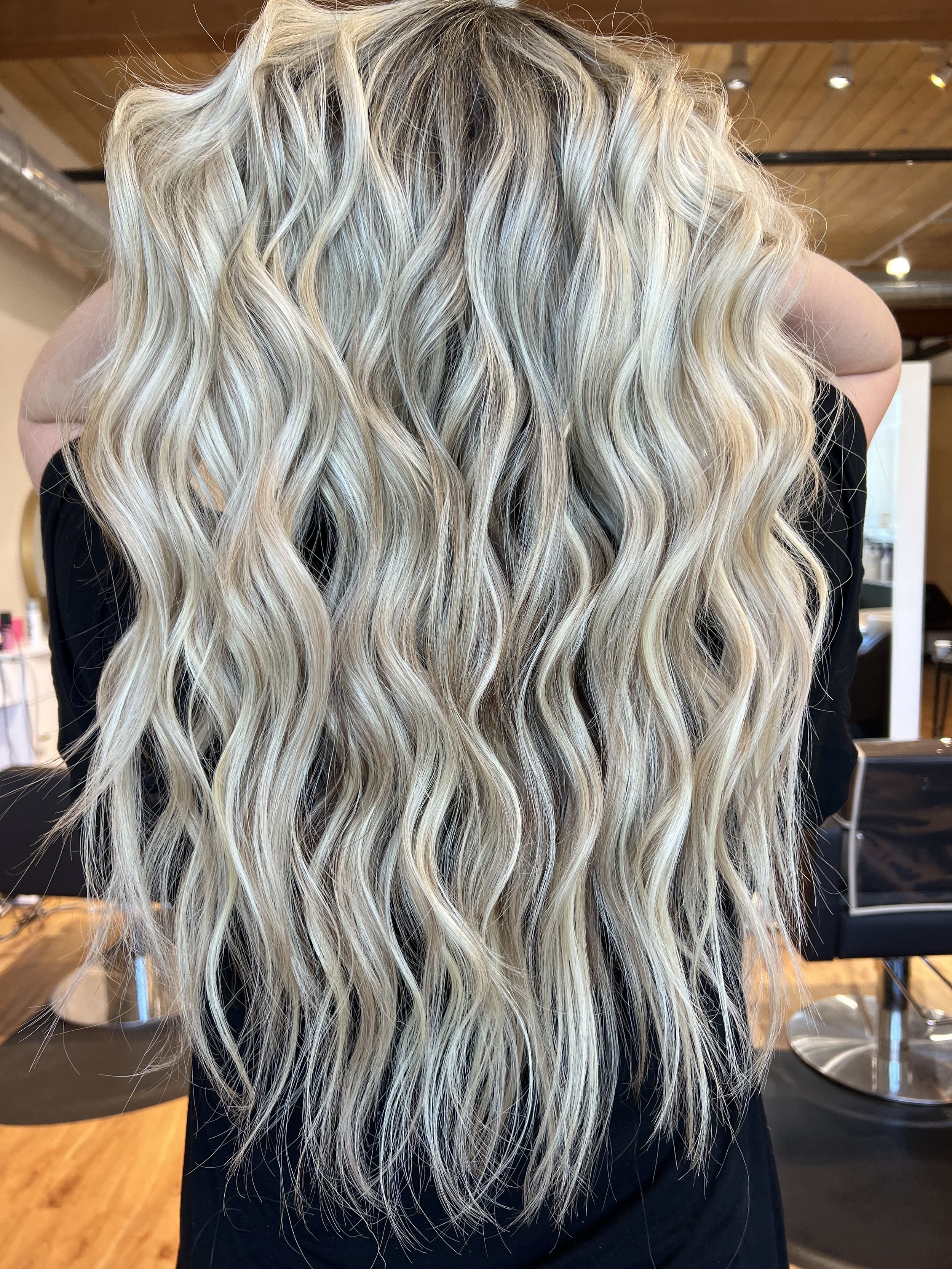 Long blonde hair extensions with soft waves at Raven Hair Studio in Palmer, AK