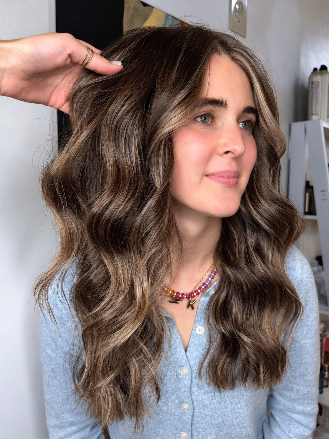 Brunette haircut with face framing highlights and styled waves at Raven Hair Studio in Palmer, AK