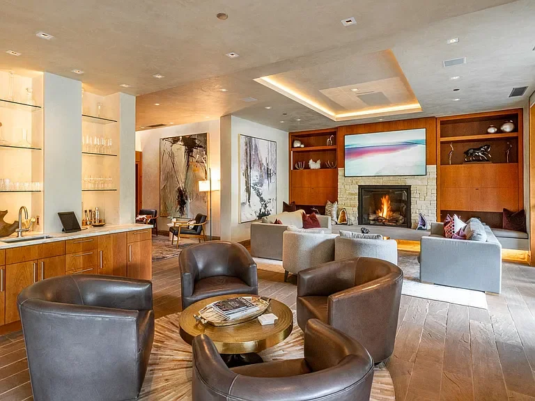 Spacious open-plan living room featuring a custom stone fireplace, wet bar, and recessed ceiling lighting at the Mother Lode in Aspen, Colorado.