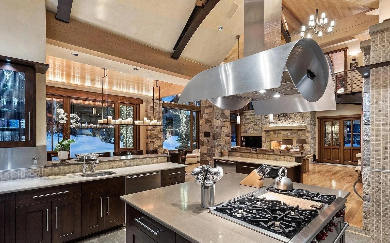 A modern, spacious kitchen with dark wood cabinets and a large center island featuring a stove top oven built by John Olson, owner of Form 44 Construction, on Crystal Lake Road in Aspen, Colorado.