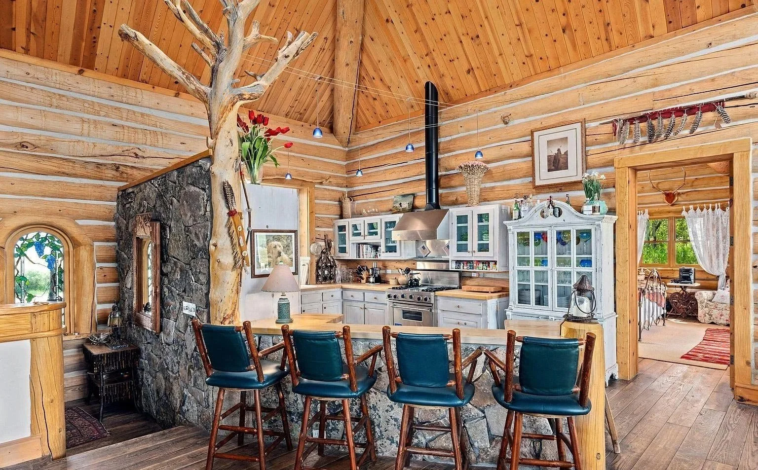 Rustic log cabin kitchen featuring a large sanded branching tree and showcasing a beautiful stone-accented bar for dining and entertaining built by John Olson, owner of Form 44 Construction, on Old Herron Road in Basalt, Colorado.