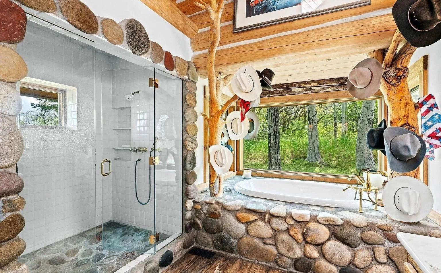 A bathroom with natural stone and wood elements including sanded tree trunks and branches looking out into a mountain forest built by John Olson, owner of Form 44 Construction, on Old Herron Road in Basalt, Colorado.