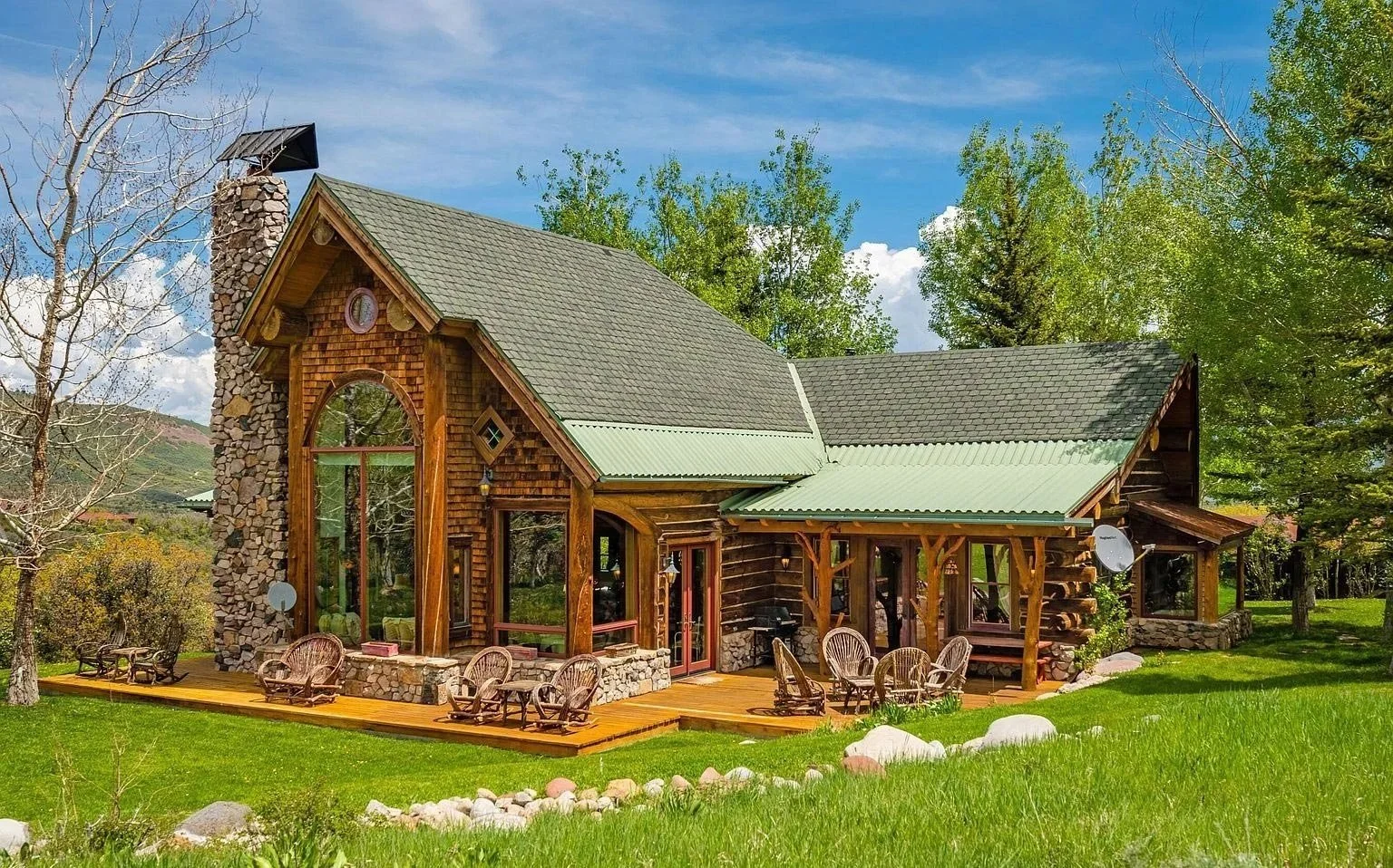 A cozy log cabin nestled amidst a lush lawn, featuring a spacious deck for outdoor relaxation built by John Olson, owner of Form 44 Construction, on Old Herron Road in Basalt, Colorado.