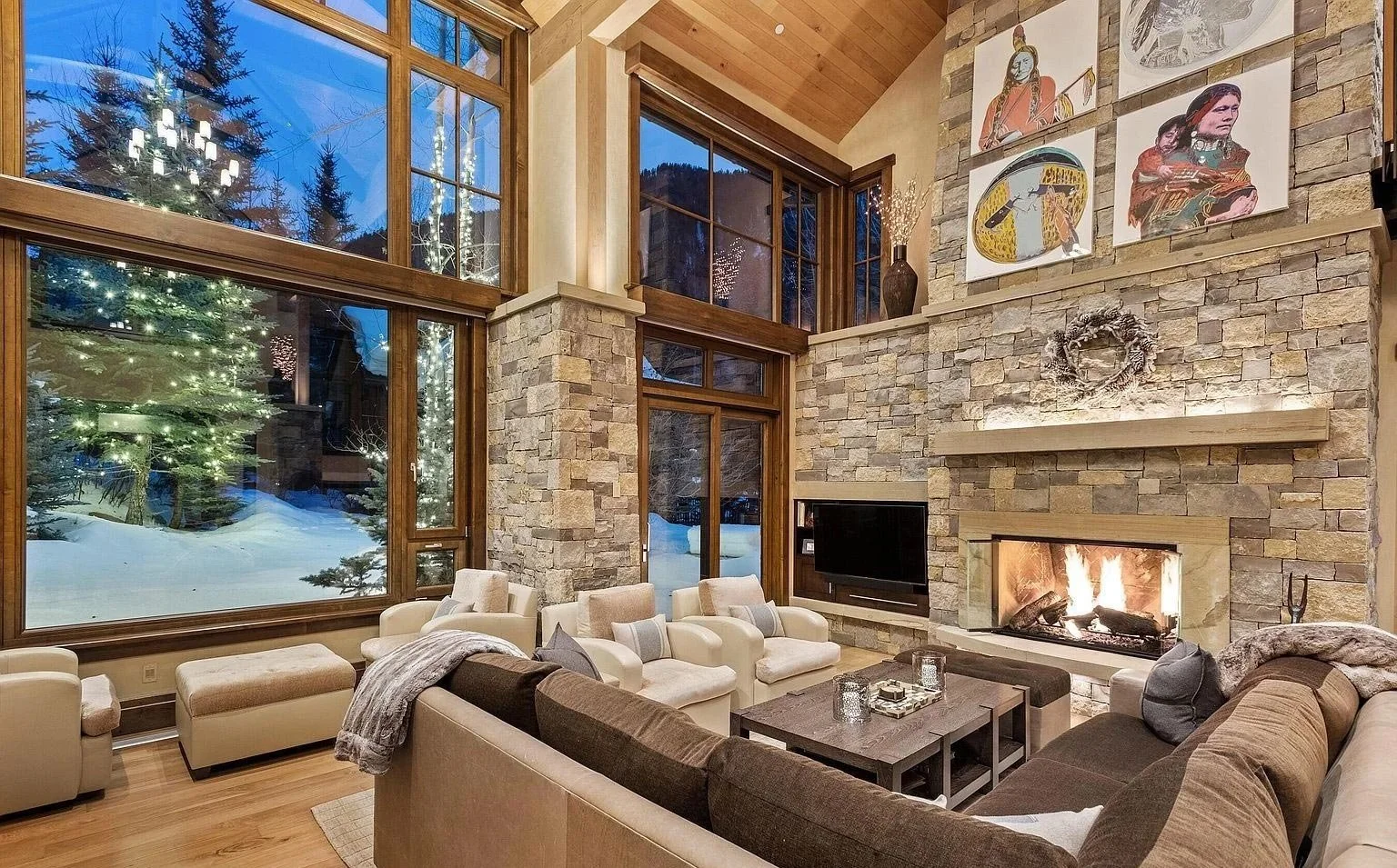A cozy, luxurious living room with a stone fireplace, vaulted ceilings, and floor-to-ceiling windows built by John Olson, owner of Form 44 Construction, on Crystal Lake Road in Aspen, Colorado.
