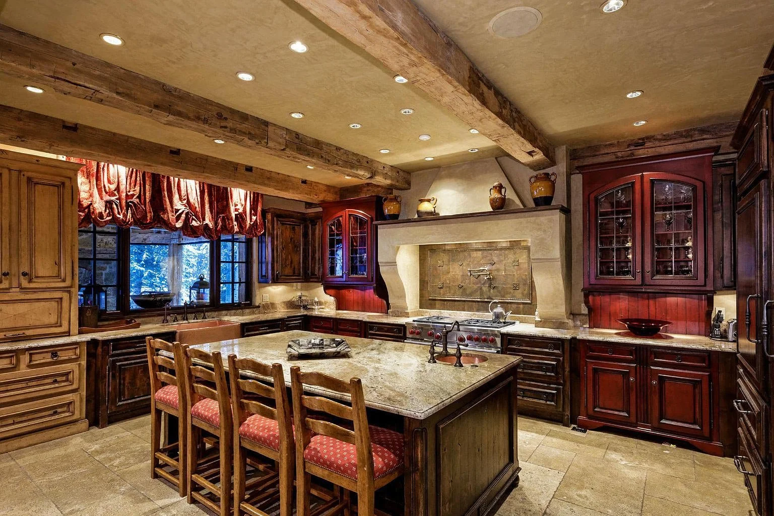 An elegant kitchen with deep cherry-colored cabinets, central island, and rustic wooden beams built by John Olson, owner of Form 44 Construction, on Spruce Ridge Lane in Snowmass Village, Colorado.