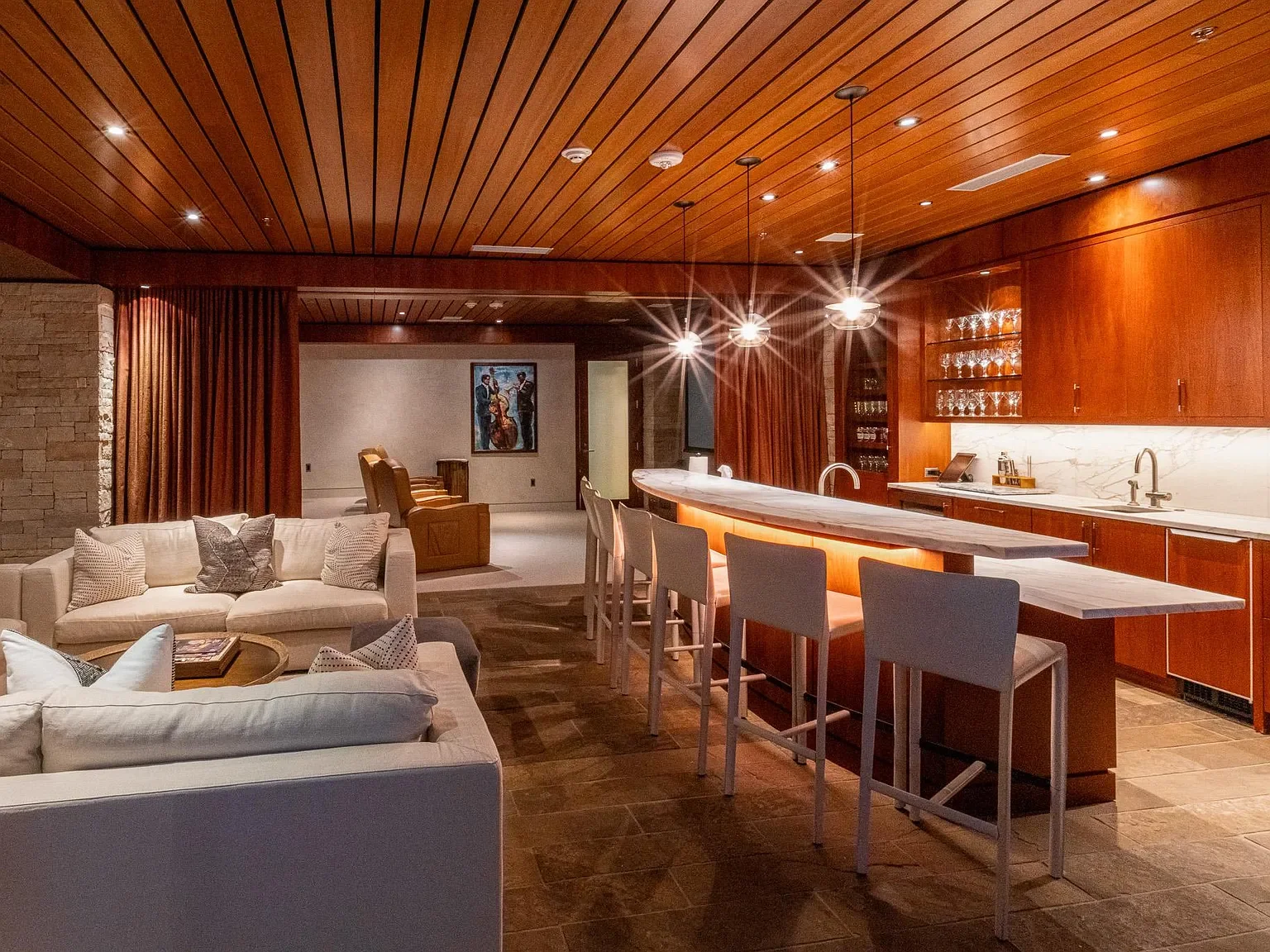 Custom wood-paneled entertainment lounge featuring a private cinema, full bar, illuminated glassware displays, and rich wood slat ceilings at The Mother Lode in Aspen, Colorado.