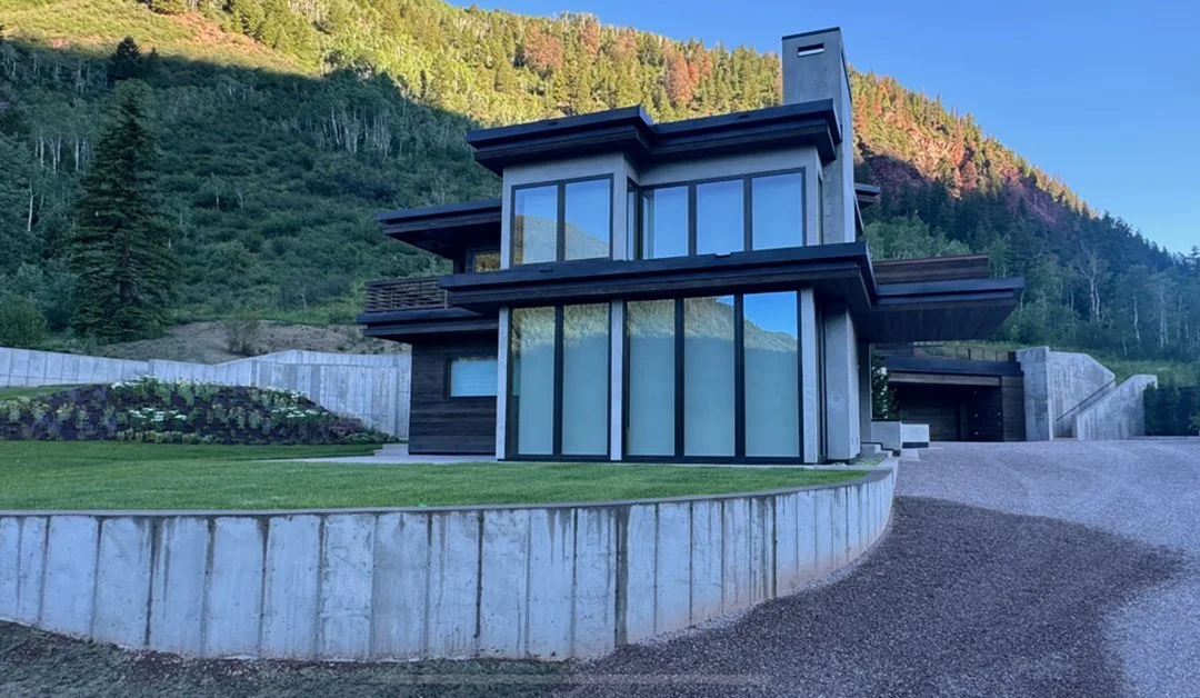 Windows of modern residential home with terraced lawn nestled in the mountains built by Form 44 Construction near Conundrum Creek in Aspen, CO