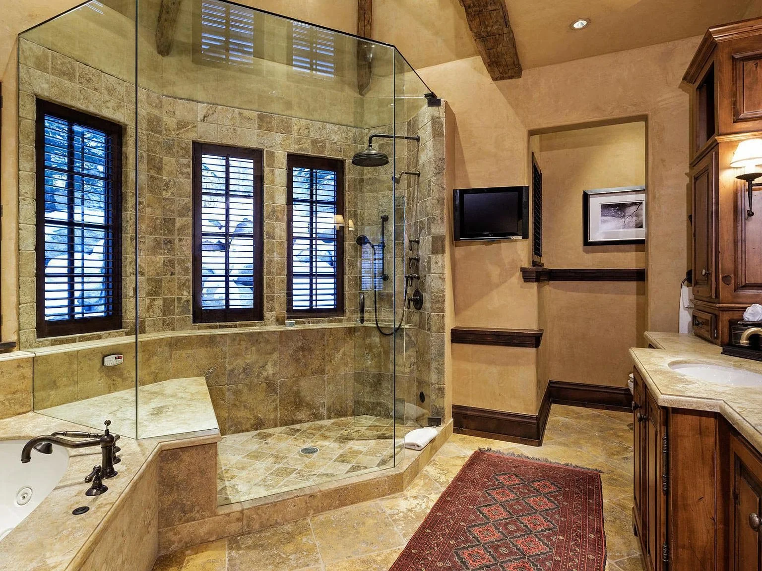 A spacious bathroom featuring a large stone tiled walk-in shower and bathtub built by John Olson, owner of Form 44 Construction, on Spruce Ridge Lane in Snowmass Village, Colorado.