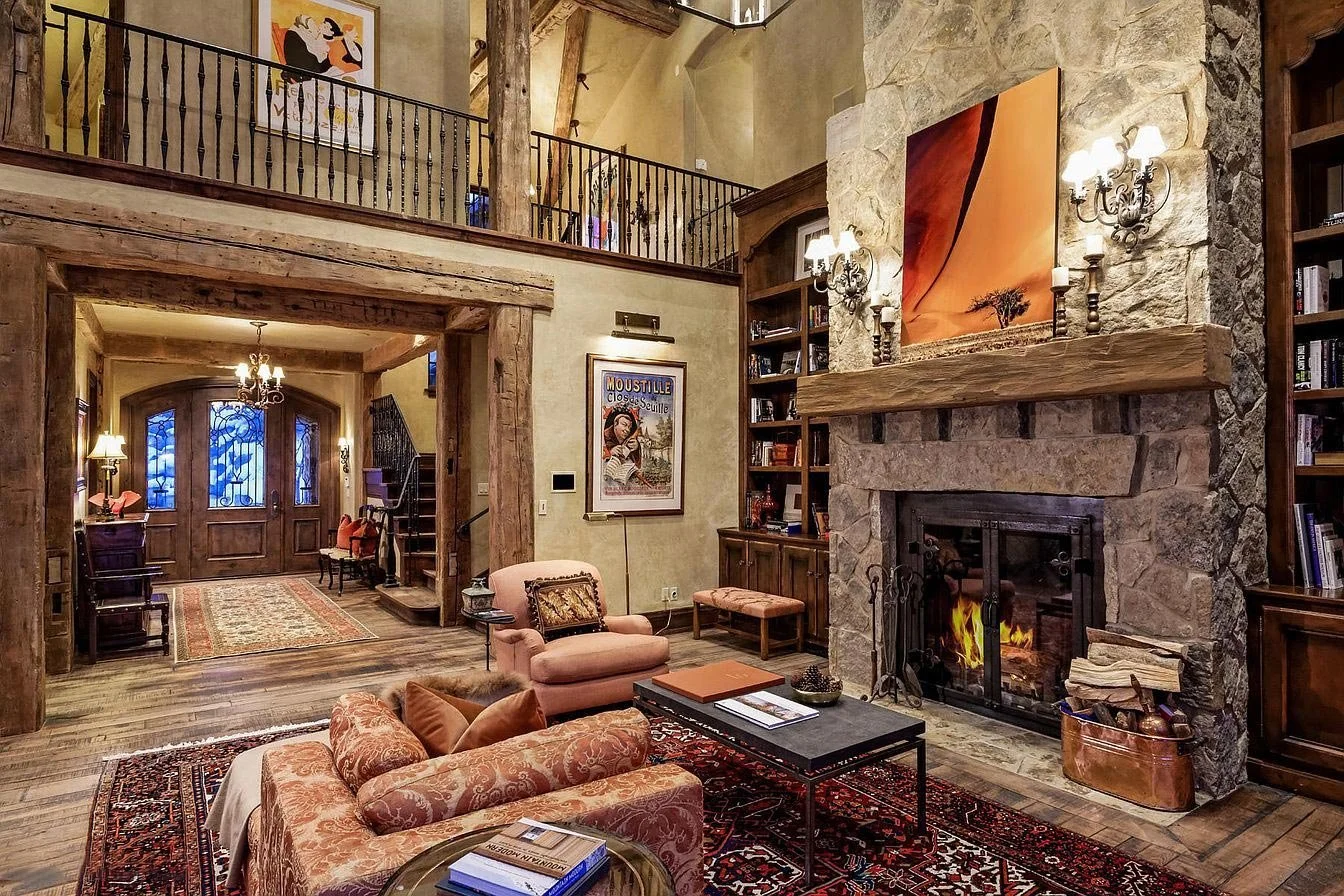 A cozy, modern mountain living room with a large fireplace and bookshelves, creating a warm and inviting atmosphere built by John Olson, owner of Form 44 Construction, on Spruce Ridge Lane in Snowmass Village, Colorado.