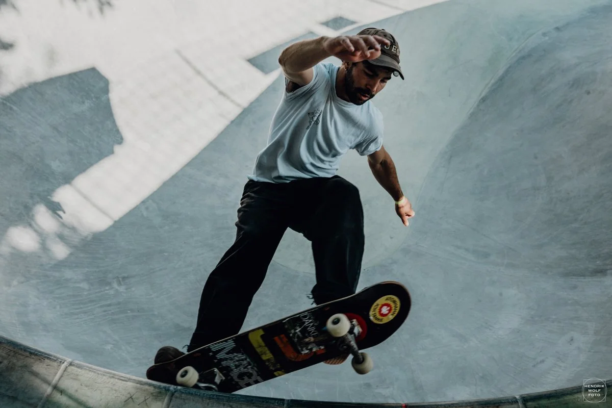 Skateboarder in a skatepark bowl performing a trick on his skateboard.