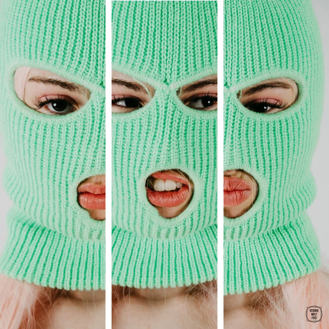 A woman wearing a bright green knit ski mask with cutouts for the eyes, mouth, and nose, showing her eyes and lips in all three sections.