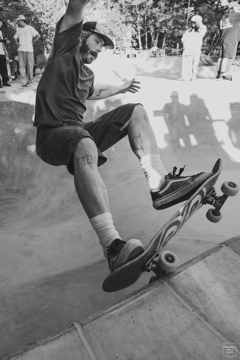 A man skateboarding in a skate park with onlookers in the background.
