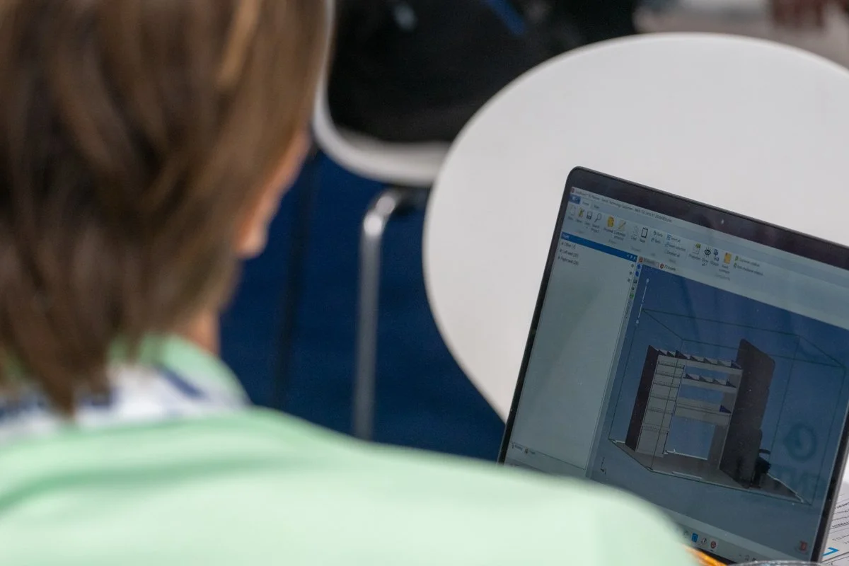 Person working on a computer with architectural design software open, showing a 3D building model.