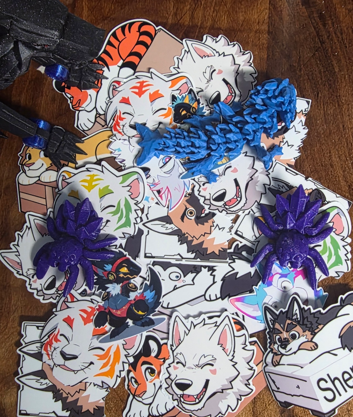 A collection of colorful stickers and 3D prints. The stickers feature various styles.