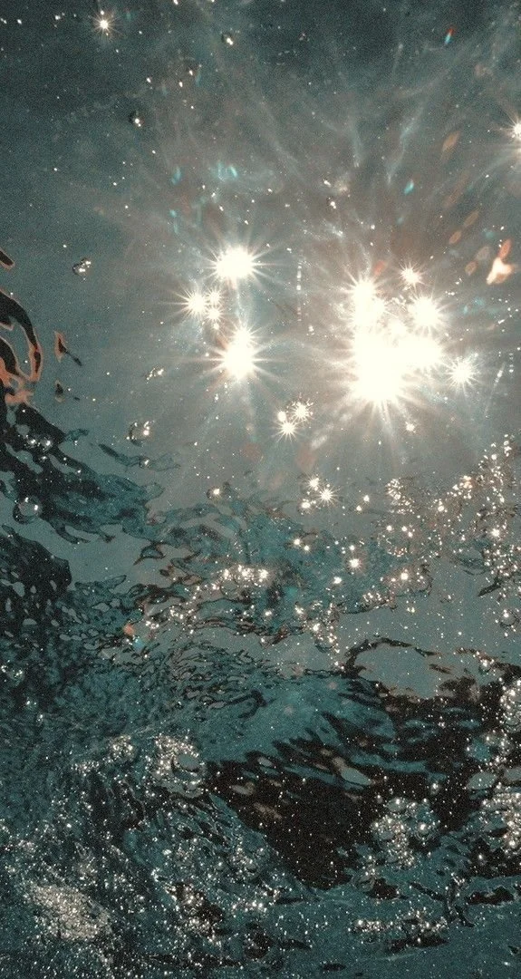 Sunlight reflecting off the surface of water, creating bright sparkles and ripples.