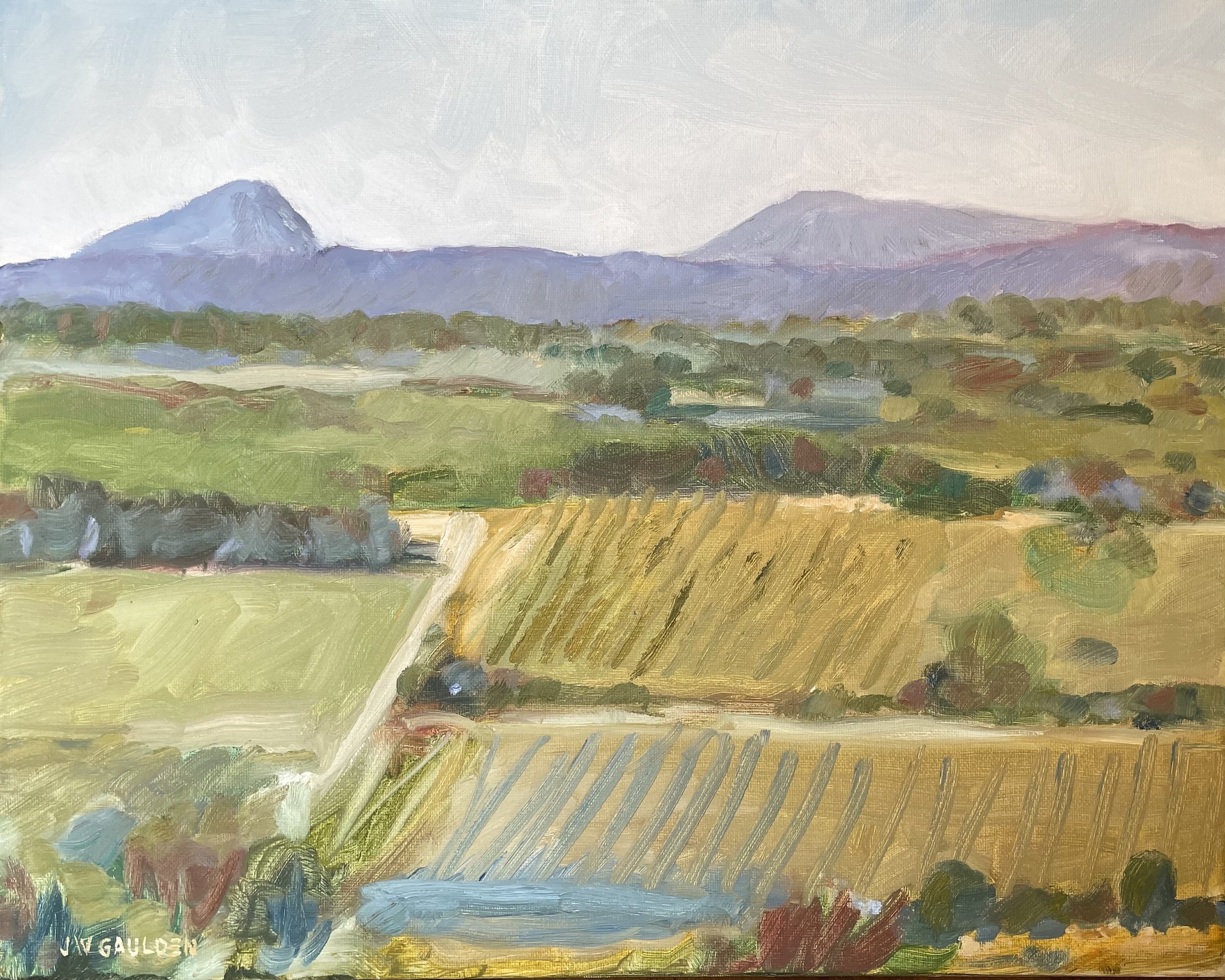 A landscape painting of mountains in the distance with a sky above, green fields and trees in the foreground, and a strip of farmland at the bottom.