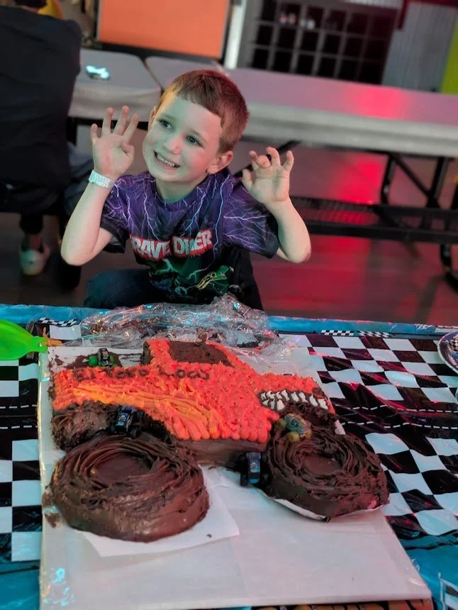 Mr. Saines, Office Manager at Mycelium Creations, celebrating behind an El Toro Loco monster truck cake.