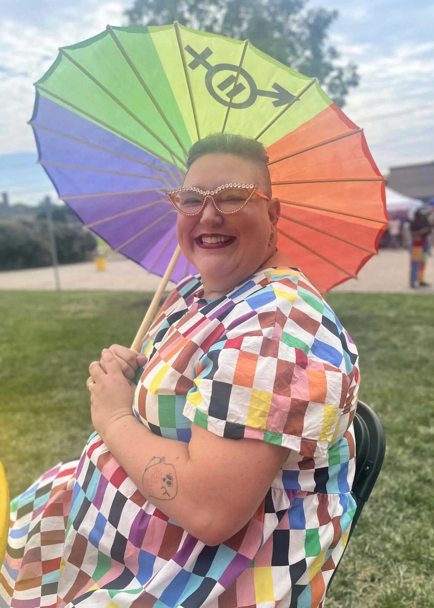 Cassie Saines founder and owner of Mycelium Creations, a Digital Marketing Company, sitting with a rainbow parasol at the Lebonan Ohio Pride Festival.